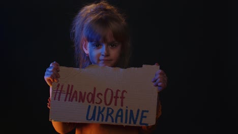 Homeless-girl-kid-showing-cardboard-massage-Hands-Off-Ukraine,-crisis-war,-no-peace,-stop-aggression