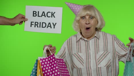 Die-Werbeaufschrift-„Black-Friday“-Erscheint-Neben-Einer-Fröhlichen-Großmutter-Mit-Einkaufstüten