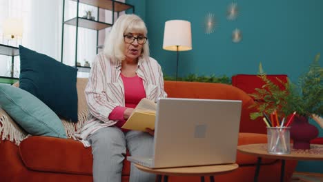 Grandmother-freelance-make-video-call-tutoring-talking-teaching-looking-at-laptop-at-home-office