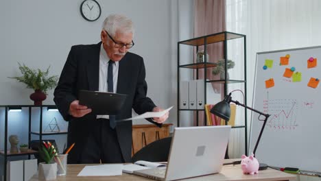 Senior-business-man-examining-graphs,-analyzing,-managing-finance-documents-report-at-home-office