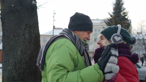 Happy-elderly-couple-grandmother-grandfather-tourists-traveling-in-European-city-near-Christmas-tree