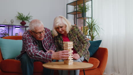 Ältere,-Alte-Großeltern,-Mann-Und-Frau,-Die-Zu-Hause-In-Blöcken-Spielen,-Holzturm-Bauen,-Brettspiel-Auf-Dem-Tisch