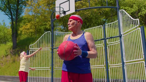 Älterer-Mann,-Großvater,-Sportler,-Posiert-Mit-Ball-Und-Blickt-Auf-Dem-Basketballplatz-Des-Spielplatzes-In-Die-Kamera