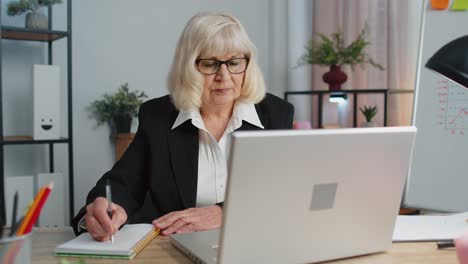 Mujer-Mayor-Madura-De-Oficina-De-Negocios-Aprendiendo-En-Línea-Escribiendo-Notas-Desde-Una-Computadora-Portátil,-Seminario-Web-En-Vivo