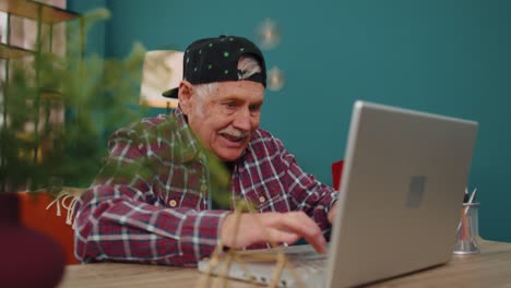 Abuelo-Hombre-Jugando-Videojuegos-De-Computadora-En-Computadora-Portátil,-Gana,-Celebra,-Sonríe-Felizmente