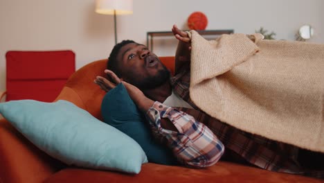 Terrified-scared-african-american-young-man-wakes-up-from-stress-nightmare-in-bedroom-at-home-sofa