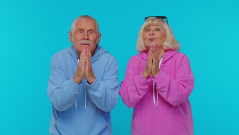 Senior-grandfather-grandmother-in-sweatshirts-praying,-looking-upward,-making-wish,-begging-apology