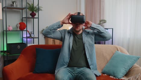 Un-Hombre-Adulto-Usa-Gafas-De-Realidad-Virtual-En-Casa,-Disfrutando-Del-Concepto-De-Video-Moviendo-Las-Manos-En-El-Aire