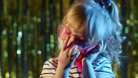 Girl-in-futuristic-glasses-talking-on-mobile-phone-with-mother-in-night-club-with-neon-blue-light