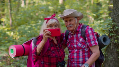 Senior-grandmother-grandfather-blogger-tourists-taking-selfie-photo-portrait-on-mobile-phone-in-wood