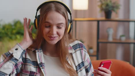 Una-Joven-Bastante-Caucásica-Con-Auriculares-Escuchando-Música-Bailando,-Cantando-En-El-Salón-De-Casa