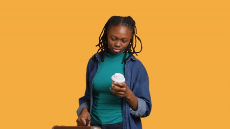 Tired-girl-travelling-with-suitcase,-drinking-coffee,-studio-background