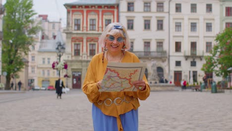 Anciana-Y-Elegante-Abuela-Turística-Caminando-Por-La-Calle,-Buscando-El-Camino-Usando-Un-Mapa-De-Papel-En-La-Ciudad