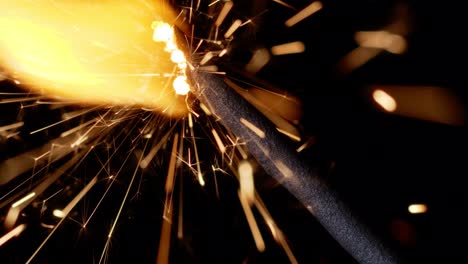 Bengal-fire,-New-Year-sparkler-candle,-sparkling-lights-burning-on-black-background,-close-up-macro