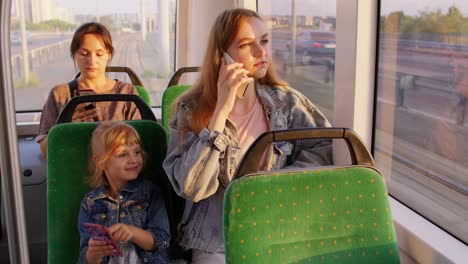 Madre-Madre-Hablando-Por-Teléfono-Móvil,-Ignorando-A-Su-Pequeña-Hija-Mientras-Está-Sentada-En-Un-Tranvía-Público