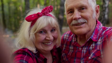 Senior-grandmother-grandfather-blogger-tourists-taking-selfie-photo-portrait-on-smartphone-in-forest