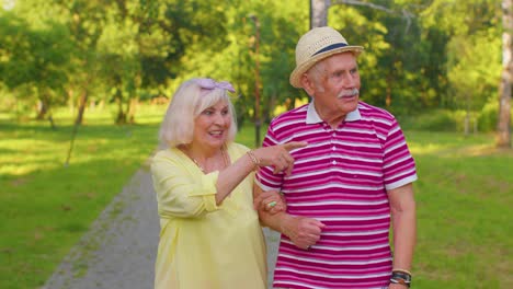 Senior-stylish-pensioners-couple-grandmother-grandfather-walking,-enjoying-time-together-in-park