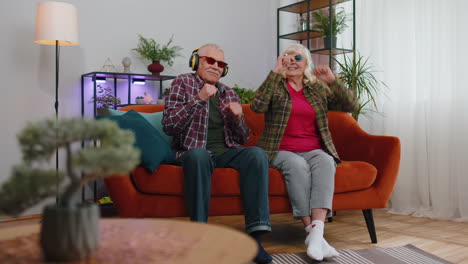 Happy-senior-grandparents-man-woman-listening-music-dancing-disco-fooling-around-having-fun-at-home