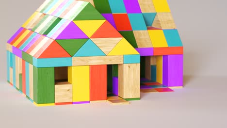 Colorful-house-being-build-from-a-pile-of-colorful-wooden-blocks.-Camera-position-pans-around-it.-Construction,-development-of-preschool-kid’s-building-imagination.-Fun-with-learning-aspects.