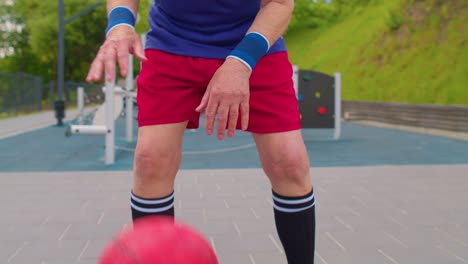 Healthy-senior-sportsman-guy-grandfather-practicing-with-ball-in-sport-playground-basketball-court