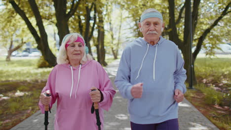 Alegre-Pareja-De-Ancianos-Abuelo,-Abuela-Entrenando-Marcha-Nórdica,-Corriendo-En-El-Parque-De-Verano