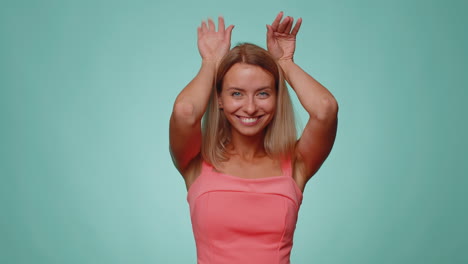 Encantadora-Joven-Divertida-Sonriendo-Amigable-Y-Haciendo-Gestos-De-Orejas-De-Conejo-En-La-Cabeza,-Bailando,-Engañando