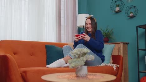 Worried-funny-addicted-woman-enthusiastically-playing-racing-video-games-on-mobile-phone-at-home