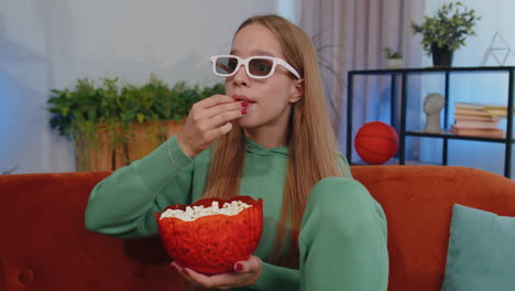 Chica-Sentada-En-El-Sofá-Comiendo-Palomitas-De-Maíz-Y-Viendo-Interesantes-Series-De-Televisión,-Juegos-Deportivos-En-Línea-En-Casa