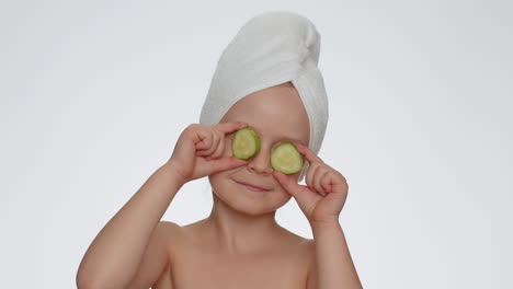 Smiling-child-girl-kid-holding-slices-of-cucumber,-covering-eyes,-natural-cosmetics,-face-skin-care