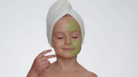 Beautiful-smiling-child-girl-kid-in-towel-on-head-applying-cleansing-moisturizing-green-mask-on-face