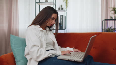 Junge-Freiberufliche-Frau,-Die-Auf-Dem-Sofa-Sitzt-Und-Den-Laptop-Schließt,-Nachdem-Sie-Die-Arbeit-Im-Wohnzimmer-Zu-Hause-Beendet-Hat