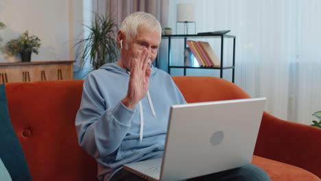 Man-sitting-on-home-couch,-looking-at-camera,-making-video-conference-call-with-friends-or-family