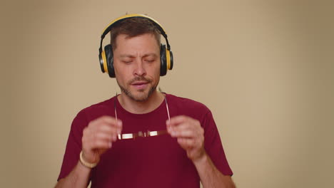 Happy-handsome-relaxed-man-listening-music-on-headphones-and-dancing-disco-fooling-around-having-fun