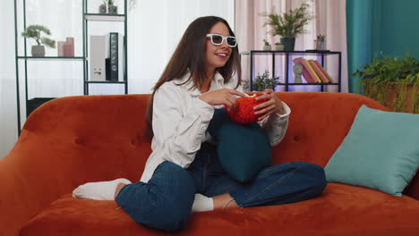 Mujer-Sentada-En-El-Sofá-Comiendo-Palomitas-De-Maíz-Y-Viendo-Interesantes-Series-De-Televisión,-Juegos-Deportivos-En-Línea-En-Casa