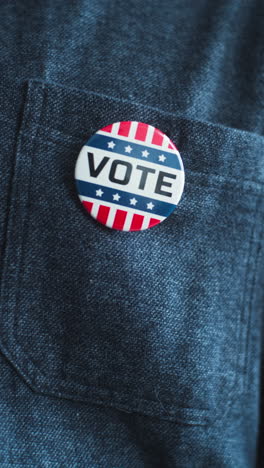 Anonymous-African-American-man-puts-on-badge-with-USA-flag-logo-and-inscription-I-Voted.-US-citizen-at-polling-station-during-elections.-National-Election-Day-in-United-States-of-America.-Close-up.