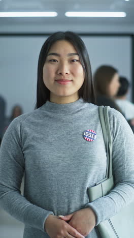 Woman-in-camouflage-uniform-stands-in-polling-station-and-looks-at-camera.-Portrait-of-female-soldier,-United-States-of-America-elections-voter.-Background-with-voting-booths.-Concept-of-civic-duty.