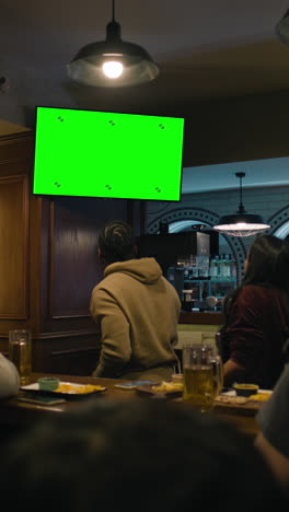 Vertical-shot-of-African-American-fan-celebrating-with-friends-when-football-team-scores-goal-and-wins-the-tournament.-Group-of-multicultural-friends-watch-live-soccer-match-sitting-in-sports-bar-or-pub.
