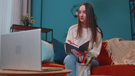 Adult-girl-student-study-at-home-on-laptop-computer-making-conference-video-call-talking-to-webcam