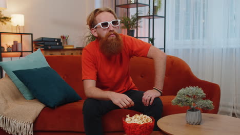 Hombre-Sentado-En-El-Sofá-Comiendo-Palomitas-De-Maíz-Y-Viendo-Interesantes-Series-De-Televisión,-Juegos-Deportivos-En-Línea-En-Casa