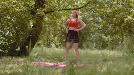 Sporty-young-woman-athlete-doing-stretching-fitness-tilts-exercises-workout-outdoors-in-sunny-park