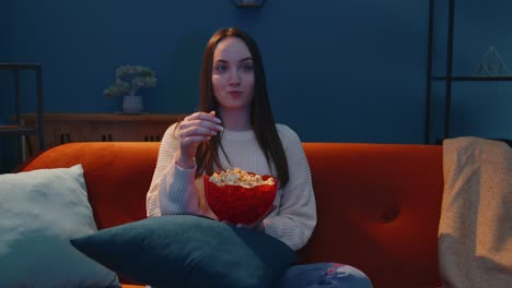 Frau-Sitzt-Allein-Auf-Dem-Sofa,-Isst-Popcorn-Und-Sieht-Sich-Zu-Hause-Eine-Interessante-Fernsehserie-Oder-Einen-Horrorfilm-An