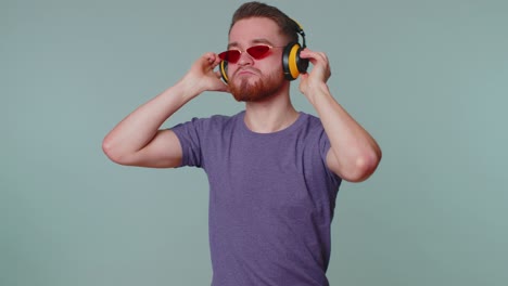 Cheerful-attractive-man-listening-music-via-headphones-and-dancing-disco-fooling-around-having-fun