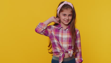 Cheerful-lovely-young-preteen-child-girl-kid-smiling,-looking-at-camera-on-studio-yellow-background