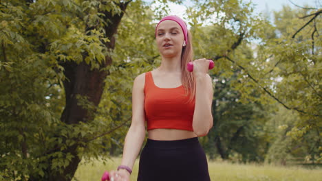 Athletic-young-sporty-fit-girl-doing-dumbbells-workout-in-sunny-park-performing-bicep-exercising