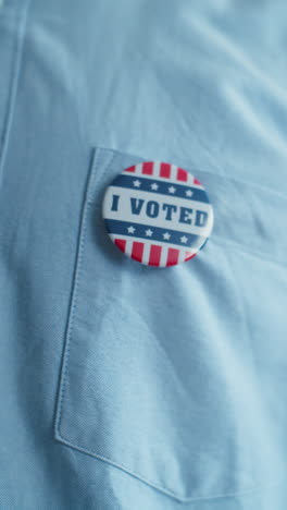 Anonymous-African-American-man-puts-on-badge-with-USA-flag-logo-and-inscription-I-Voted.-US-citizen-at-polling-station-during-elections.-National-Election-Day-in-United-States-of-America.-Close-up.