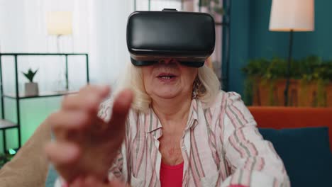 Senior-woman-using-virtual-reality-VR-app-headset-helmet-to-play-simulation-3D-360-video-game-online