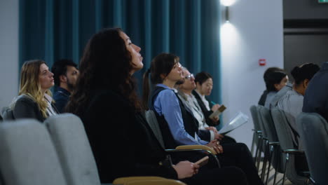 Journalists-sit-and-write-answers-in-notebooks-from-politician-during-press-campaign-in-the-conference-hall.-Caucasian-male-media-representative-raises-his-hand-and-asks-questions-during-interview.