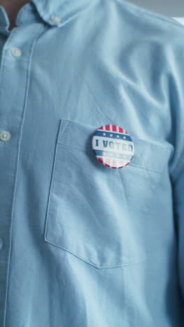 Anonymous-African-American-man-puts-on-badge-with-USA-flag-logo-and-inscription-I-Voted.-US-citizen-at-polling-station-during-elections.-National-Election-Day-in-United-States-of-America.-Close-up.