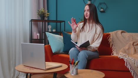 Adult-girl-student-study-at-home-on-laptop-computer-making-conference-video-call-talking-to-webcam