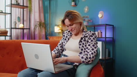 Thoughtful-young-woman-freelancer-got-an-idea-and-typing-on-laptop-netbook-celebrating-victory